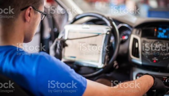 Automobile computer diagnosis. Car mechanic repairer looks for engine failure on diagnostics equipment in vehicle service workshop